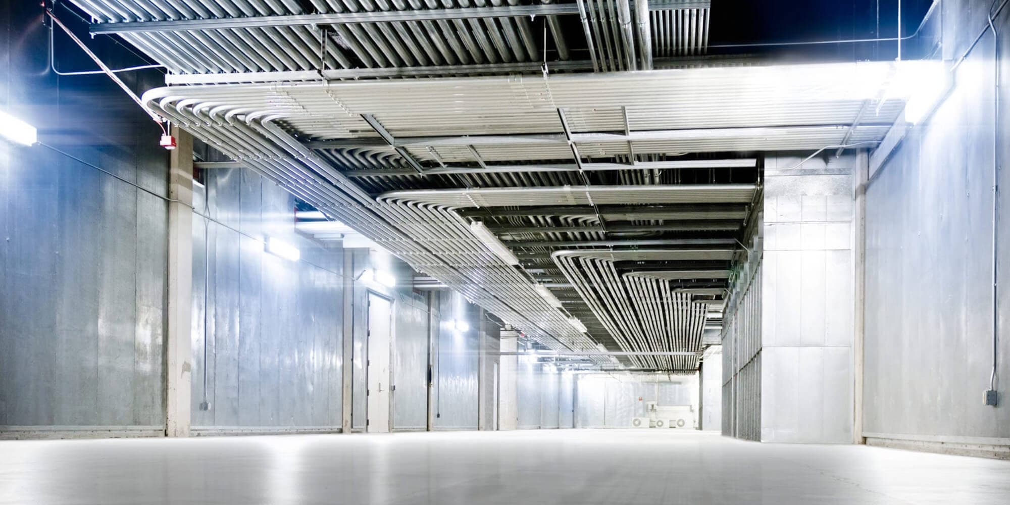 Low-angle shot of an empty corridor with many electrical conduits running along the ceiling