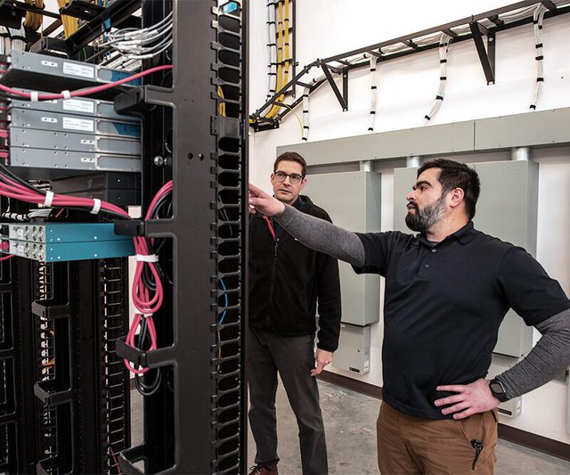 people inspecting wires on a server rack