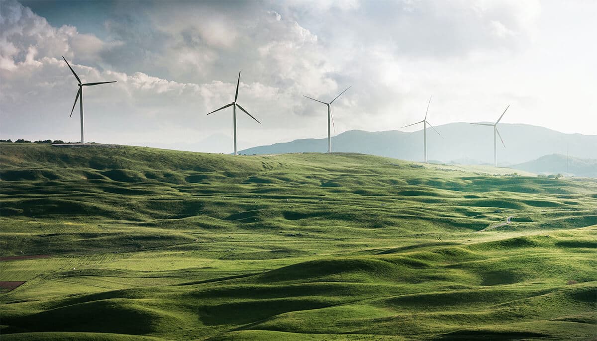 a line of windmills in the background of rolling green hills