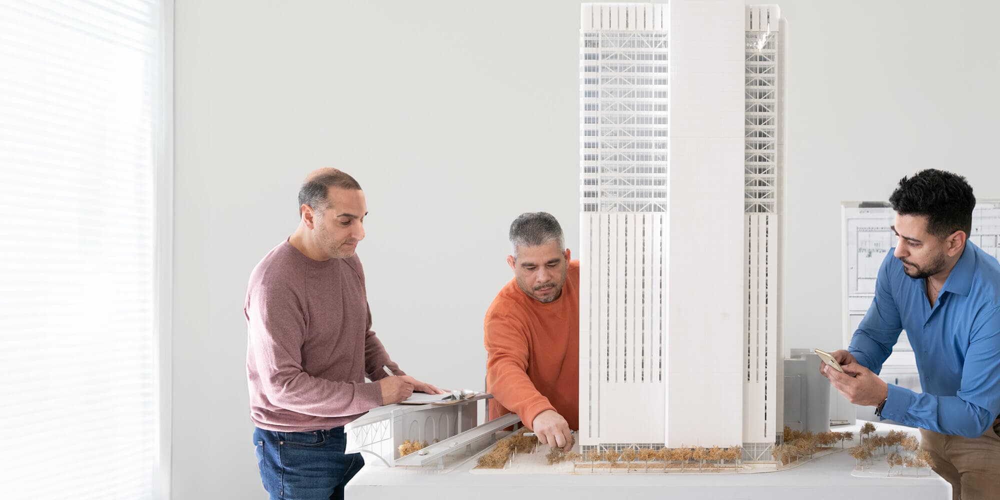 Three business people interacting with a physical model of Sabey's Manhattan Data Center building