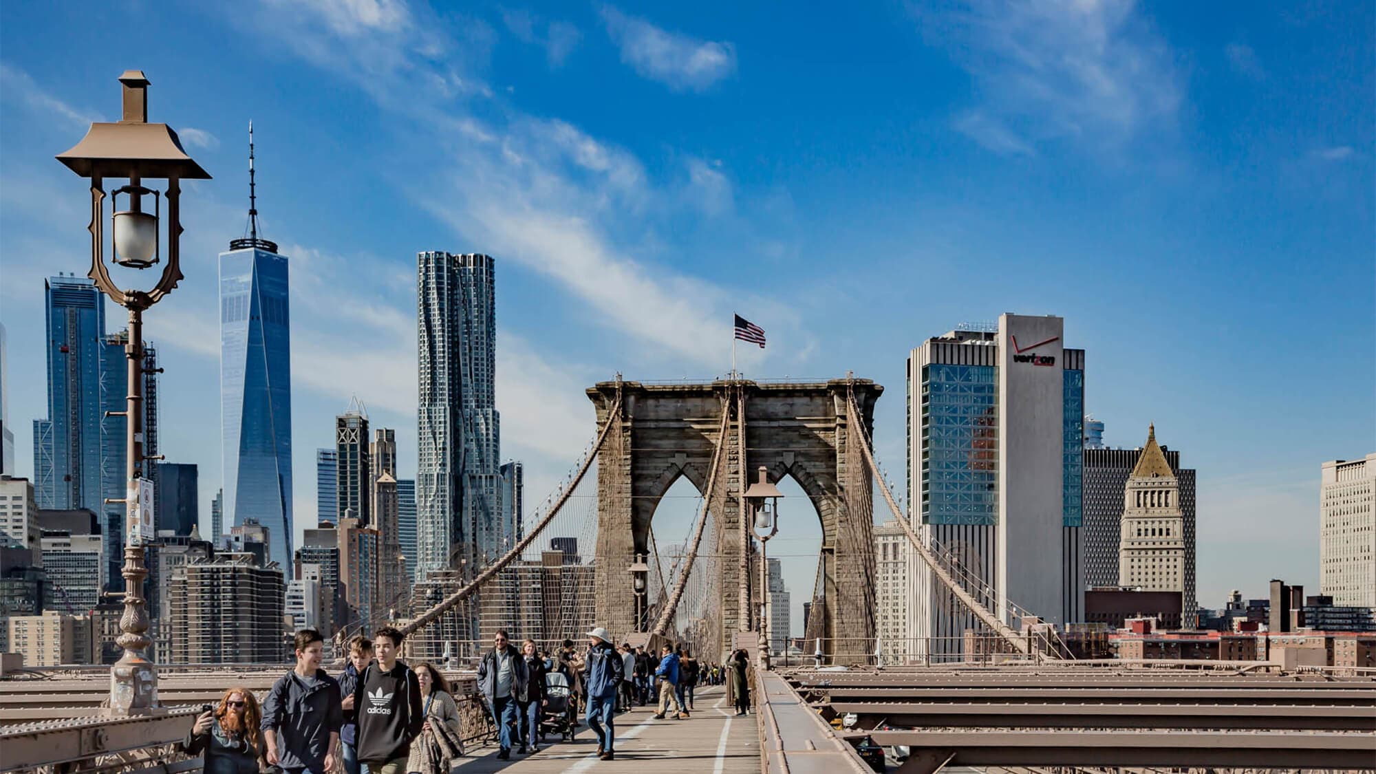 People crossing the Brooklyn Bridge with 375 Pearl Street in the background