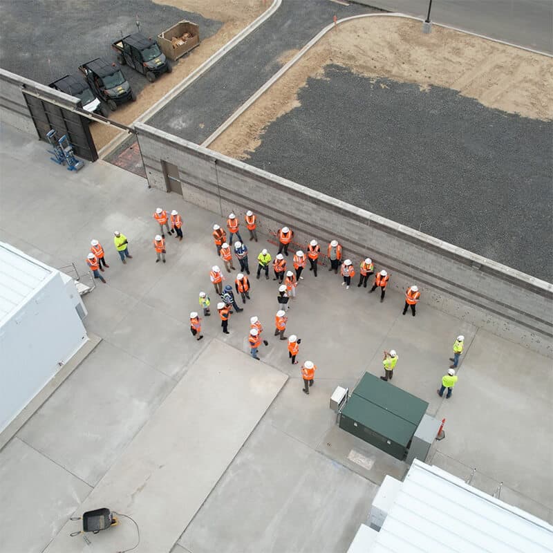 A group of about 30 construction team members having a meeting, shot from above
