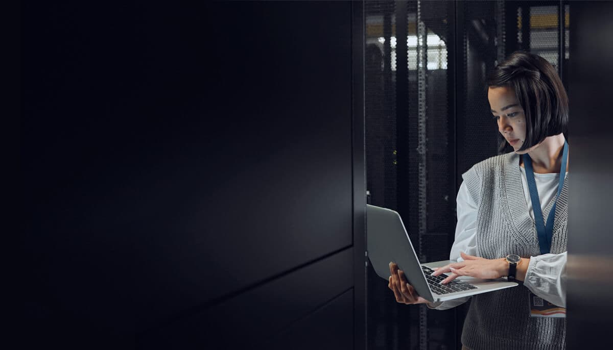 IT worker with laptop computer in a dark data center