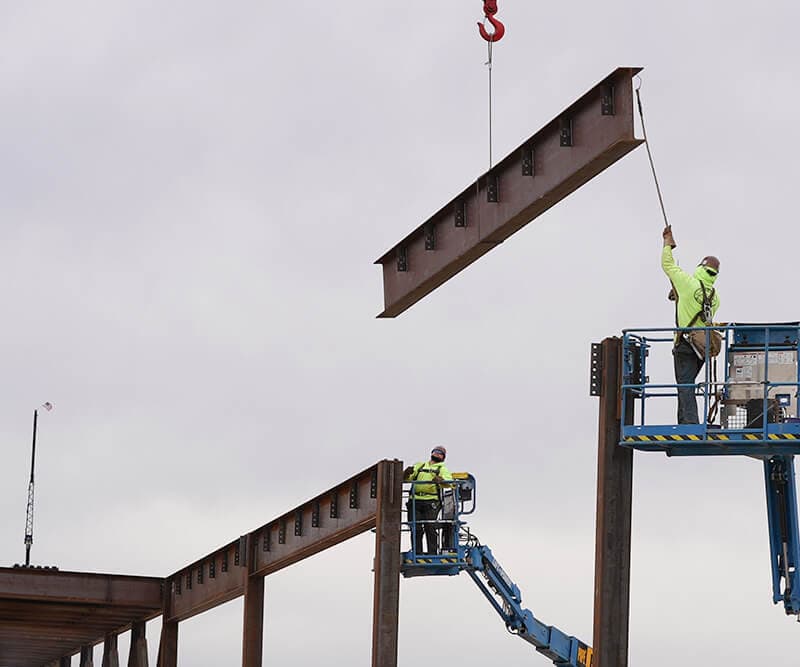 Construction team guiding an I-beam into place