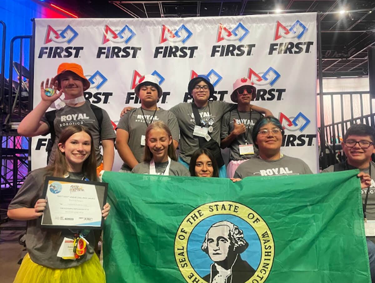 Team of middle school students hold up a Washington State flag at a robotics competition