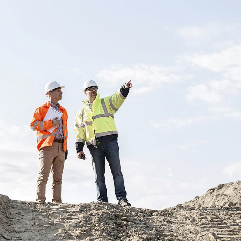 Two builders standing near a construction site and talking