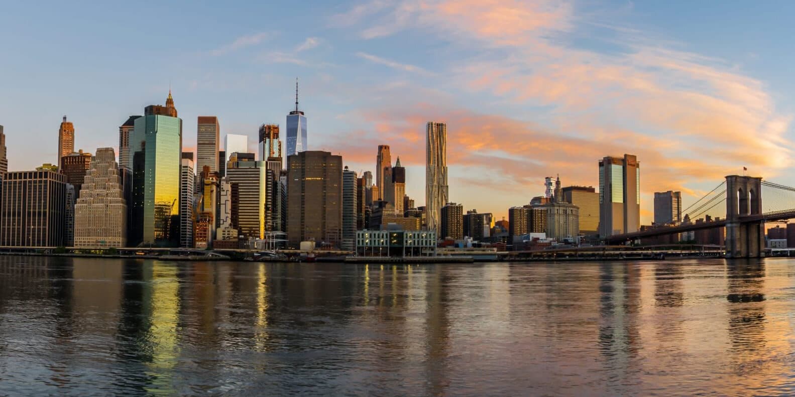 A wide shot of the Manhattan skyline with water in the foreground.