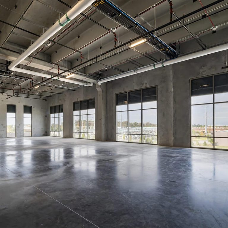 Empty room of a building with concrete floors and exposed pipes