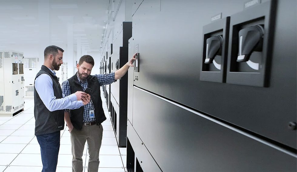 people reviewing a phone in a server room