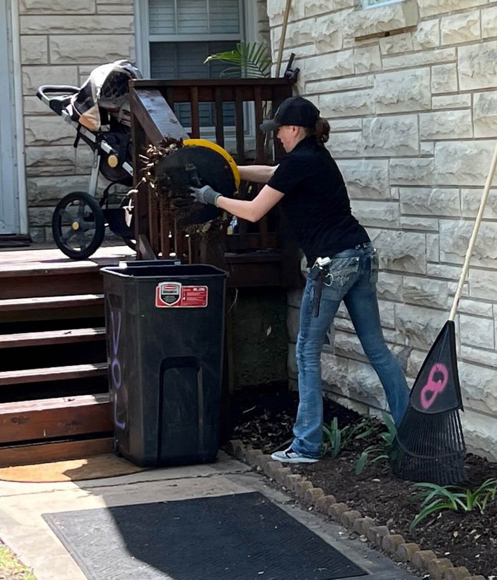 Volunteer dumps dead leaves into a yard waste bin
