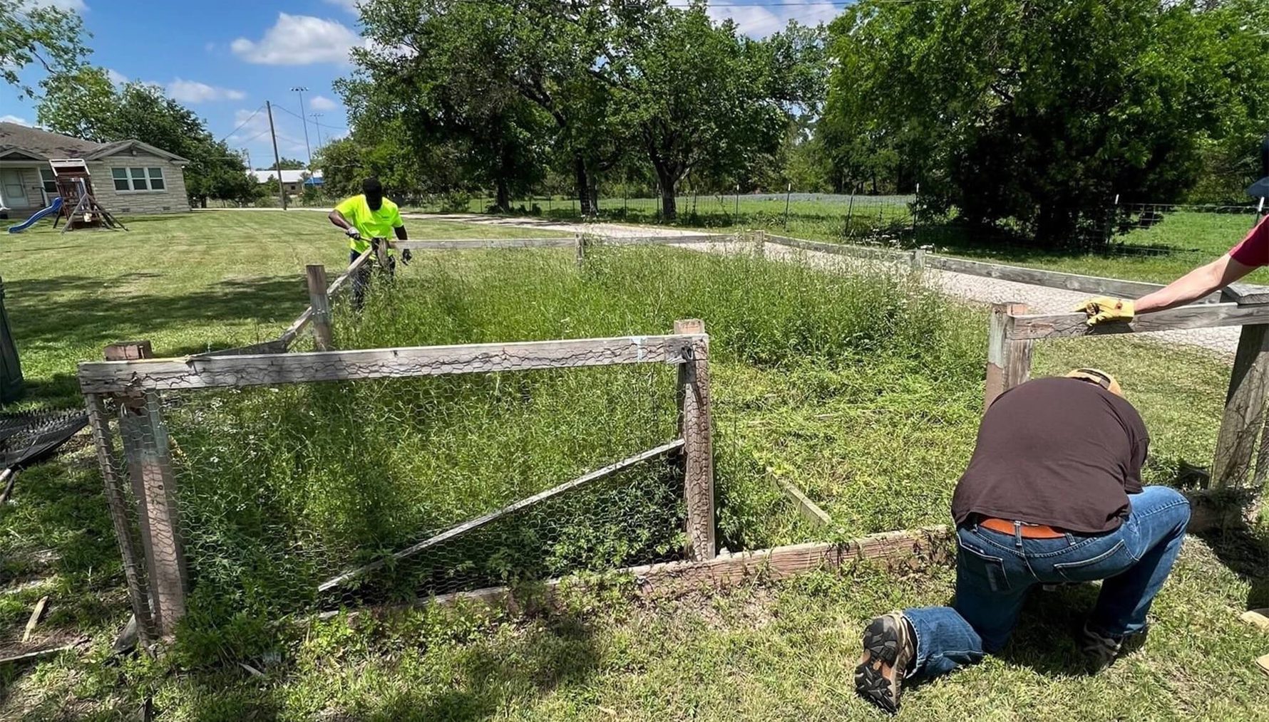 Volunteers taking apart an old fence and doing yardwork