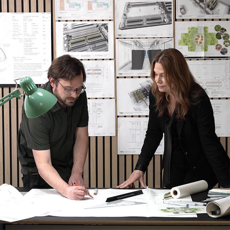 Two designers collaborating over a set of architectural drawings