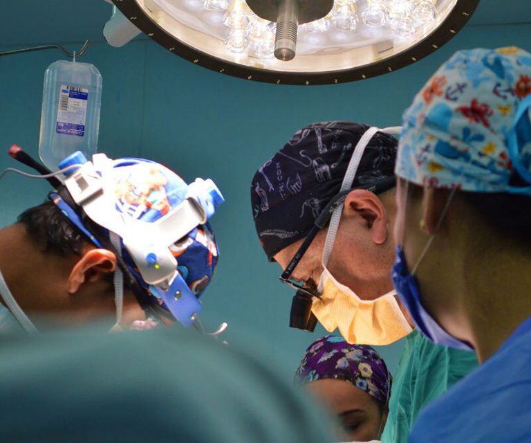 Doctors in masks looking over an operating table.